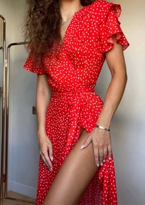 Detailed view of a red polka dot wrap dress featuring ruffle sleeves and side split