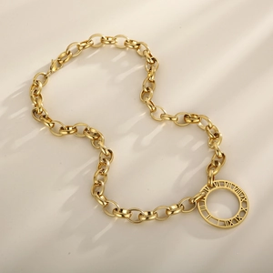 Macro detail of gold chunky chain necklace with roman numeral engraved round pendant