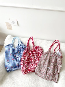 Detailed close-up of floral canvas tote bags with drawstring handles on a white rug
