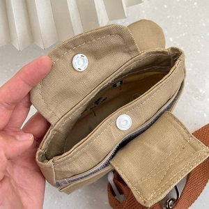 Detalle de la mochila para perro en lona caqui con cierre de botón a presión