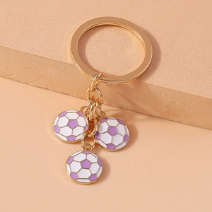 Close-up of golden sports keychain featuring three purple and white enamel football charms