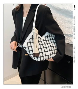 Close-up of black and white checkered tweed tote bag with leather trim and embroidered strap