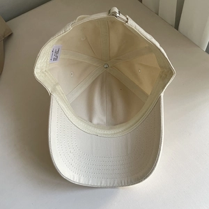 Inside view of beige cotton baseball cap featuring internal sweatband and metal buckle