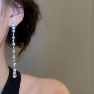 Close-up of model wearing silver tassel earrings with sparkling teardrop zircons