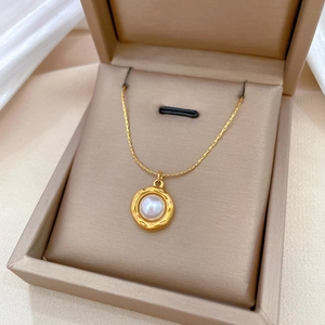Minimalist titanium steel gold necklace with hammered circle and white pearl in a jewelry box