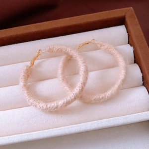 Detail of pink wool-wrapped hoop earrings with gold metal clasp in jewelry box