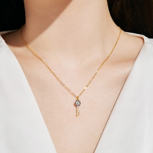 Close-up of a gold S925 sterling silver key necklace with sparkling evil eye zircon