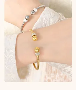 Close-up of gold and silver open bangles with pavé crystal beads and snake bone texture