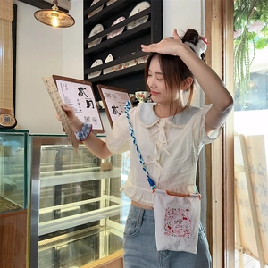 Gros plan d'un mini sac bandoulière en toile blanche avec broderies étoile et cerise
