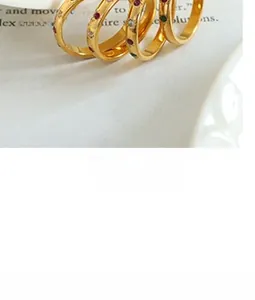 Detail of four gold rings with colored gemstones on a white ceramic tray macro shot