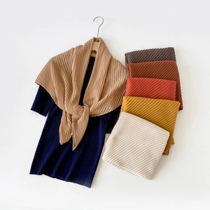 Detailed close-up showing a collection of pleated linen-feel square scarves in various colors