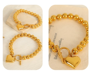 Detailed close-up of a polished gold heart pendant and toggle clasp on a bead bracelet