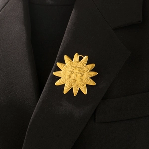 Detail of vintage gold sunburst brooch featuring a smiling face on black blazer