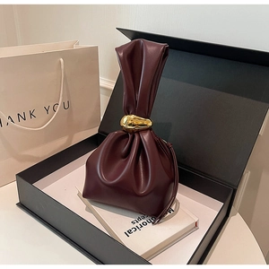 Detail view of wine red pleated bucket bag with elegant gold metal ring handle
