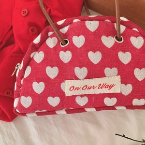 Macro shot of red heart-pattern canvas bag with leather strap and zip closure