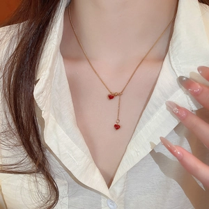 Elegant model wearing a gold Y-shaped necklace with red heart pendants on a white shirt