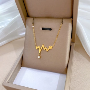 Macro shot of gold heartbeat necklace with heart and diamond pendant in a gift box