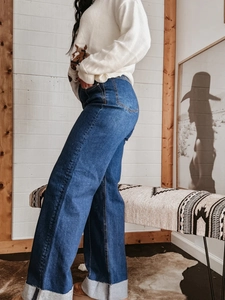 Detail van een high-waist jeans met wijde pijpen, omgeslagen zoom en vintage denim textuur