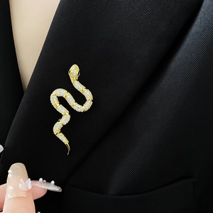 Detailed view of a gold-plated snake brooch with cubic zirconia on a black suit lapel
