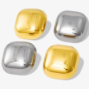 Macro view of polished square earrings in gold and silver finishes with mirrored surface