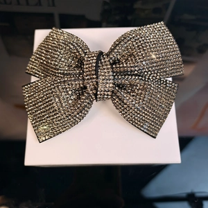 Macro detail of dark grey rhinestone bow hair clip with sparkling crystal pavé finish