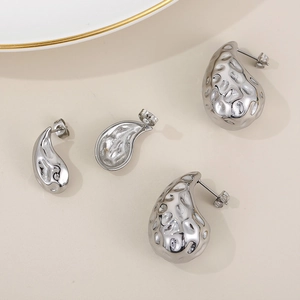 Detailed view of silver water drop earrings with hammered metal texture and glossy finish