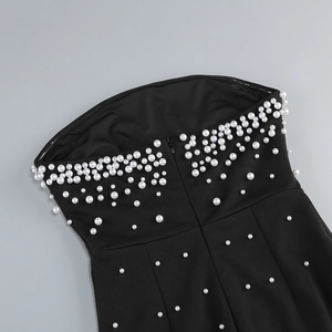 Détail de perles blanches sur robe bustier noire montrant la texture du tissu