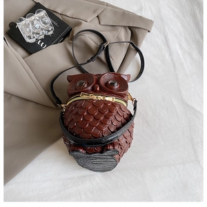 Detail of owl-shaped crossbody bag featuring textured feather patterns and gold zippers