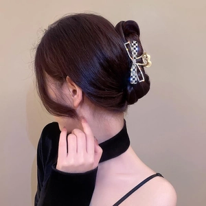 Détail de la pince papillon en métal argenté avec strass et motif à damier noir