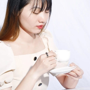 Close-up of titanium steel ring with Roman numerals on model holding a coffee cup