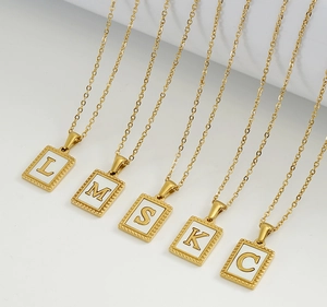 Detail of 18K gold stainless steel necklaces with shell inlay and various letter pendants