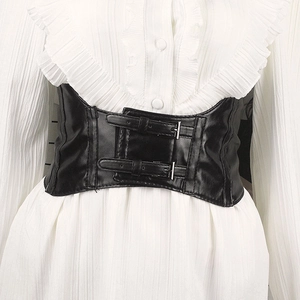 Detail of black faux leather wide corset belt with double metal buckles on white shirt