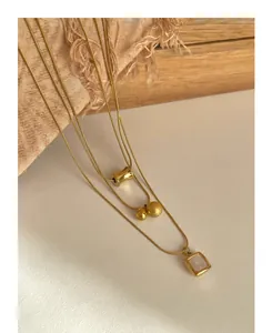 Close-up of triple-layered gold necklaces with mother of pearl shell and metal pendants