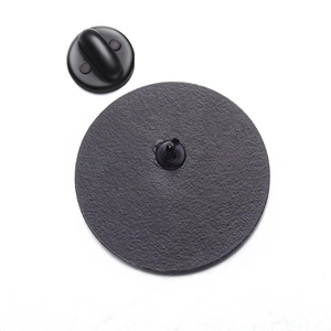 Detail of the back of a yellow duck pin showing the metal needle and black rubber clutch