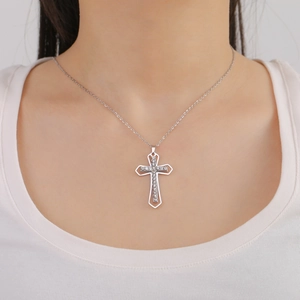 Polished silver stainless steel cross pendant with sparkling zircons worn on a model