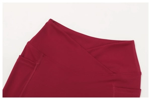 Dettaglio dei pantaloni da yoga rossi con vita a V incrociata e cucitura tasca laterale
