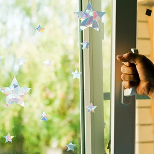 Detailed star-shaped rainbow prism window film reflecting sunlight on a glass window
