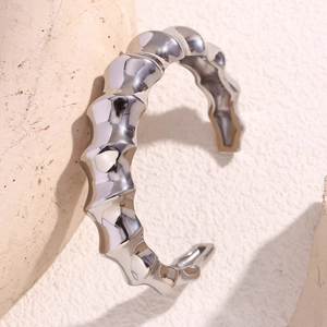 Close-up of a silver spiral bamboo-joint bangle with wavy metallic texture on stone