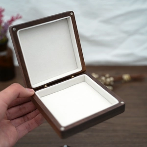 Exquisite square solid wood jewelry box with cream velvet lining held by hand
