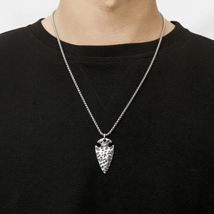 Close-up of a men's vintage steel spearhead pendant with weathered texture on model