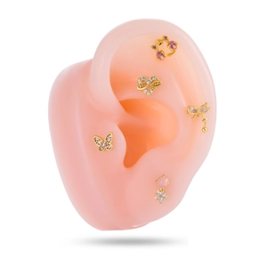 Parure de boucles d'oreilles dorées avec nœud cœur et papillon sur modèle d'oreille