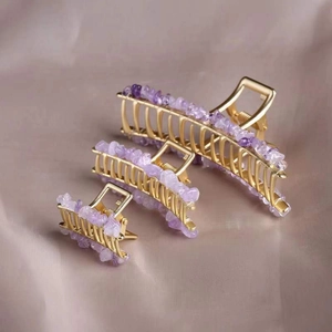 Three sizes of amethyst crystal hair claws in gold alloy frames on beige fabric