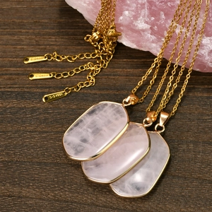 Three vintage rose quartz geometric pendants on gold titanium steel chains over wood