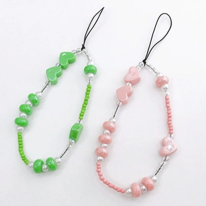 Detailed view of handmade pearlescent heart beaded phone straps in pink and green colors