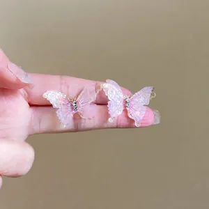 Nahaufnahme von eleganten rosa Harz-Schmetterlingsohrringen mit funkelnden Strasssteinen