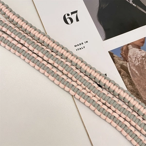 Vue détaillée de la bandoulière tressée à la main en rose et gris avec motif en croix