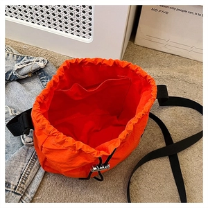 Top view of orange drawstring bucket bag interior with internal open pocket detail