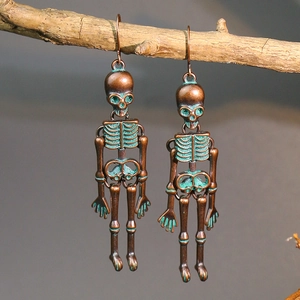 Close-up of vintage bronze skeleton earrings with green patina hanging on a branch
