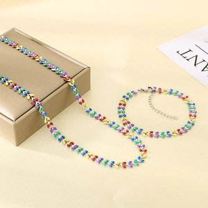 Detail of colorful enamel leaf necklace and bracelet set on a beige fabric background