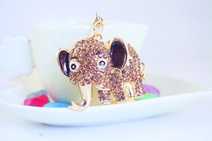 Macro view of gold elephant keychain featuring brown rhinestones and purple enamel ears